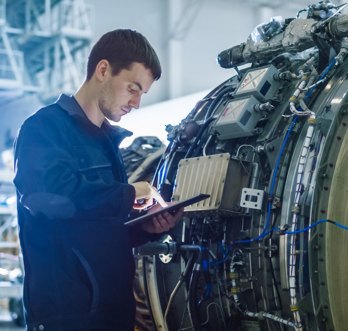 Contractor technician using a tablet during aerospace maintenance work